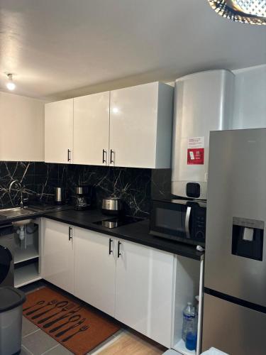  La cuisine est équipée de placards blancs et d'un réfrigérateur. dans l'établissement Comfortable Apartment in Bondy - 2 Bedrooms, à Bondy