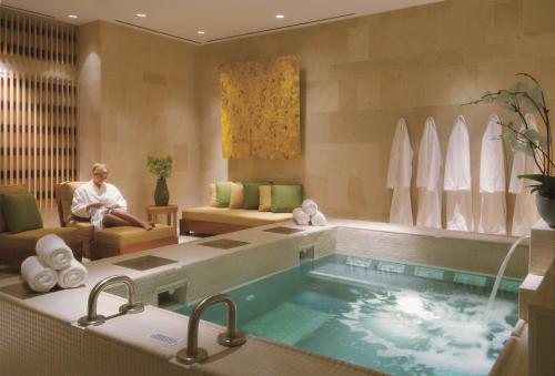 uma mulher sentada numa sala com uma piscina em Four Seasons St. Louis em Saint Louis