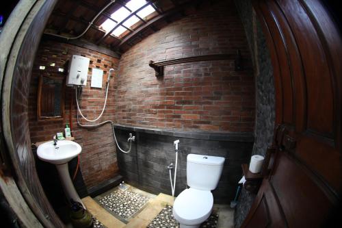 a brick bathroom with a toilet and a sink at Omah Garengpoeng Guest House in Borobudur