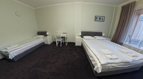 two beds in a room with a desk and a table at Rakhiv Hotel & Apartments in Rakhiv