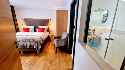 a bedroom with a bed with red pillows and a chair at Alp-Chalet in Hirschegg