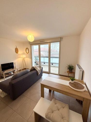 a living room with a couch and a table at Proche Genève - Cosy Appartement in Reignier