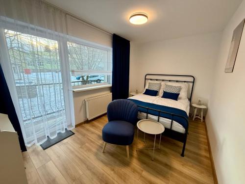 Un dormitorio con una cama, una silla y una ventana en Ostoja Pod Szrenicą, en Szklarska Poręba