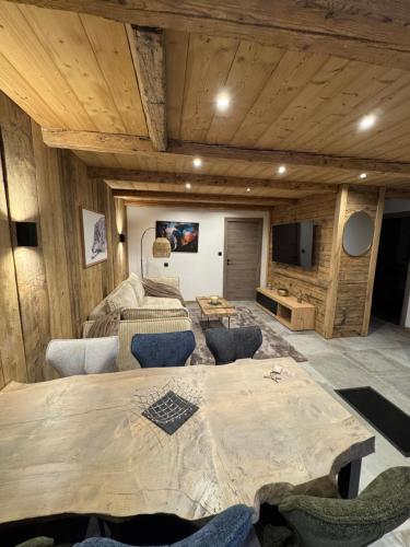 a large wooden room with a table and a tv at Le hameau des roches in Gérardmer