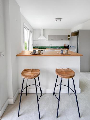 a kitchen with two stools in front of a counter at Immersion Naturelle à Castelnaud in Castelnaud-de-Gratecambe