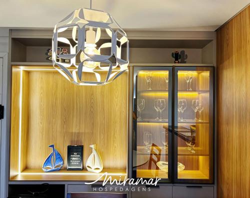 a chandelier hanging over a glass cabinet with wine glasses at Blue Beach Residence in Cabedelo
