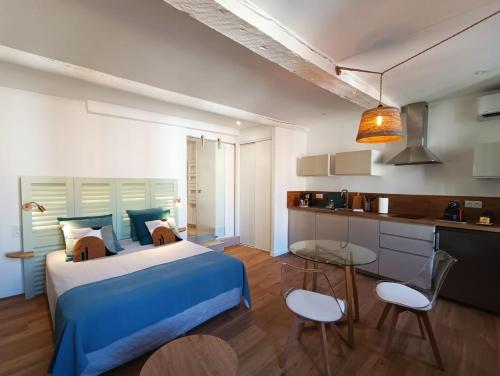 - une chambre avec un lit bleu, une table et des chaises dans l'établissement Centre historique studio rénové avec vue, à LʼIsle-sur-la-Sorgue