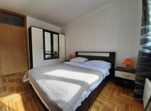 een slaapkamer met een groot wit bed en een houten vloer bij Apartman Vinka in Trogir