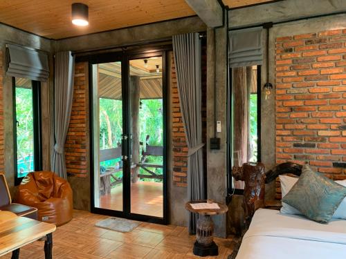 a room with a bed and a brick wall at Wooden House,Rustic charm in quiet area in Ban Khlong Chi Lat