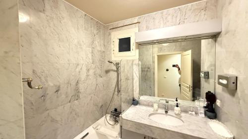 une salle de bain blanche avec un lavabo et une douche dans l'établissement Les balcons de Victor Hugo, à Paris