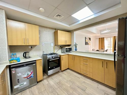 a kitchen with wooden cabinets and a stove top oven at Perfect Home Away from Home 3 BR - Maids in Ras al Khaimah