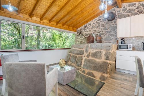 a kitchen with a stone wall and a table and chairs at Moinhos do Coto - by Proguest in Vila Verde
