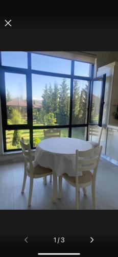 a table and chairs in a room with a large window at Villa Lux in Quba in Quba