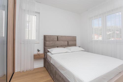 a white bedroom with a large bed and two windows at Luxury Apartment Providenca with Private Rooftop Terrace in Podstrana