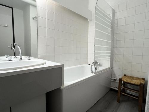 La salle de bains blanche est pourvue d'un lavabo, d'une baignoire et d'un miroir. dans l'établissement Résidence Le Tourmalet - maeva Home - Appartement 2 pièces 8 personnes - Confort MAE-0351, à La Mongie