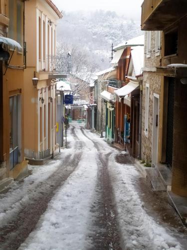 a snow covered street in a town with buildings at Διώροφο πέτρινο σπίτι με θέα Agiasos Classic Stone House in Agiásos