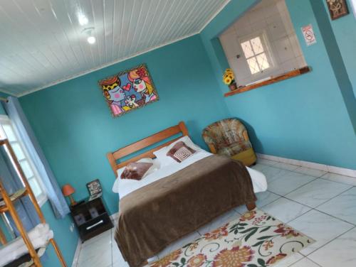 a bedroom with a bed and a blue wall at Pousada Cantinho da Mi & Teco in Campos do Jordão