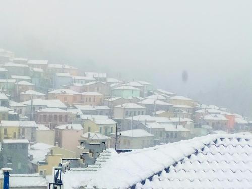 a city covered in snow with houses and roofs at Διώροφο πέτρινο σπίτι με θέα Agiasos Classic Stone House in Agiásos