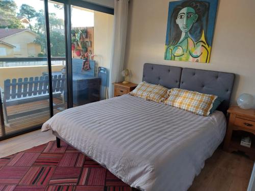 une chambre avec un lit avec un tableau sur le mur dans l'établissement Appartement avec balcon au pied du port, à Capbreton