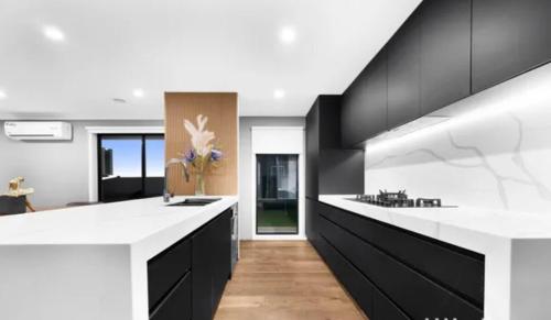 a kitchen with black and white counters and a white counter top at Sanctuary Lakes Holiday house in Point Cook