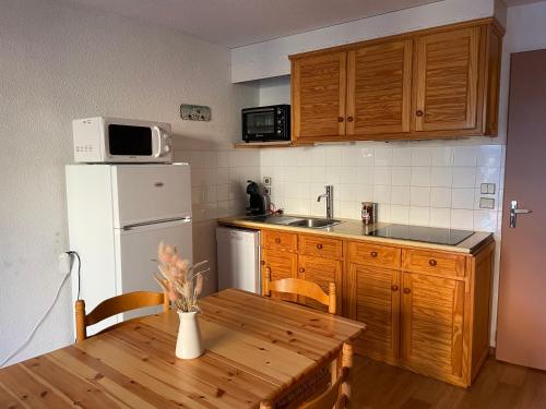 une cuisine avec une table en bois et un réfrigérateur blanc dans l'établissement Studio cabine, aux Angles