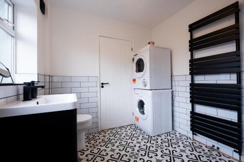 Un baño blanco con lavadora y secadora. en Cosy Home 2 Bedroom House Birkdale, en Southport