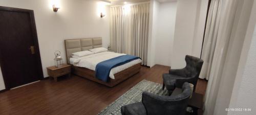 a bedroom with a bed and two chairs at The Zen Abode in Nāldera