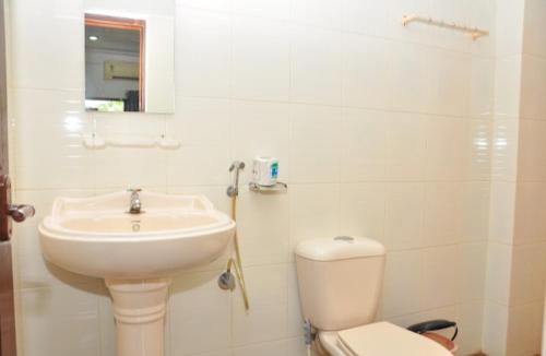 a white bathroom with a sink and a toilet at Cosmic Holiday Inn in Kovalam