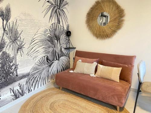 - un canapé dans le salon orné d'une fresque murale de palmiers dans l'établissement Nouveau Studio Oasis, à Chasseneuil-du-Poitou