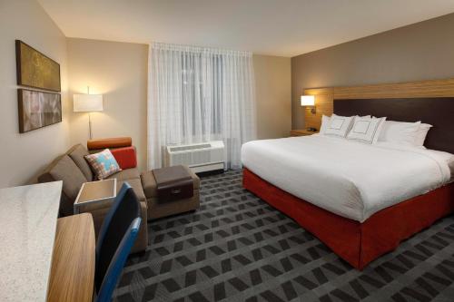 une chambre d'hôtel avec un grand lit et un canapé dans l'établissement Towneplace Suites By Marriott Louisville Northeast, à Louisville
