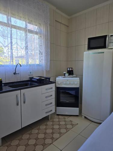 a kitchen with a refrigerator and a stove and a sink at Edificio Hayannes - 01 Quarto - Cozinha - Banheiro - Garagem Coberta - Self Check in - Taxa Para Hospede Com Pets in Maringá