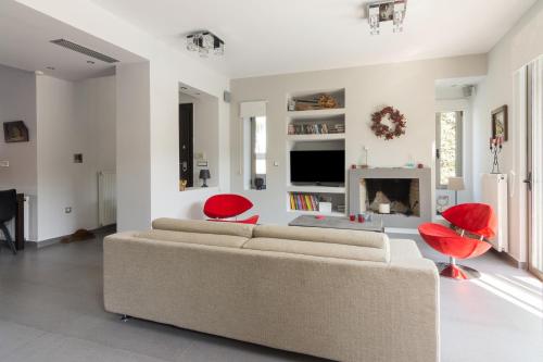 a living room with a couch and two red chairs at Luxury modern villa with swimming pool, Athens Riviera in Lagonissi