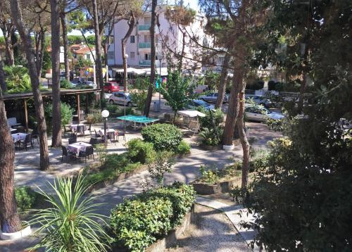 a park with tables and chairs and trees at B&B Promenade Hotel Simple con Piscina in Milano Marittima