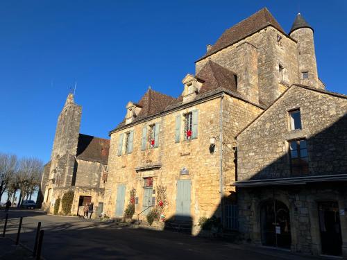 un grand bâtiment en pierre avec une tour en arrière-plan dans l'établissement Maison du peintre, à Domme