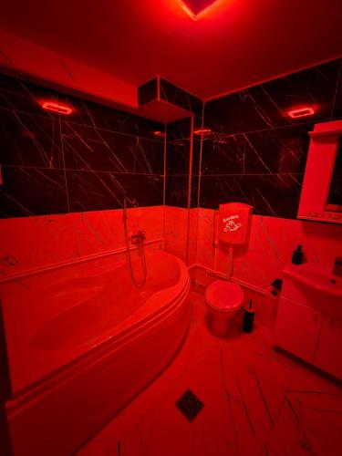 a red bathroom with a toilet and a tub and a sink at Doksim Luxury Apartments 202 in Pirot