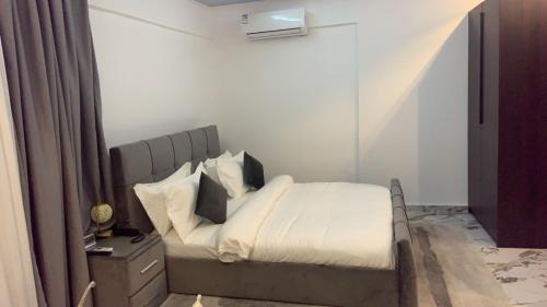 a bedroom with a bed with white sheets and pillows at Scarlett Apartments in Monrovia