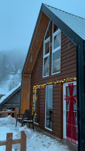 a cabin in the snow with a red bow in the window at Villa in Rugove, Kosovo in Lekaj