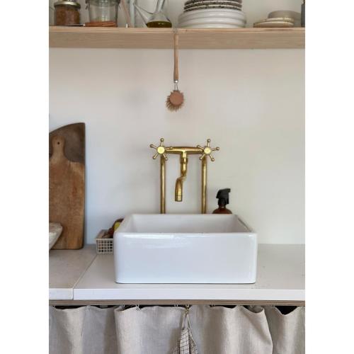 a white sink in a kitchen with a gold faucet at Atelier Blå houses in Rösselvik
