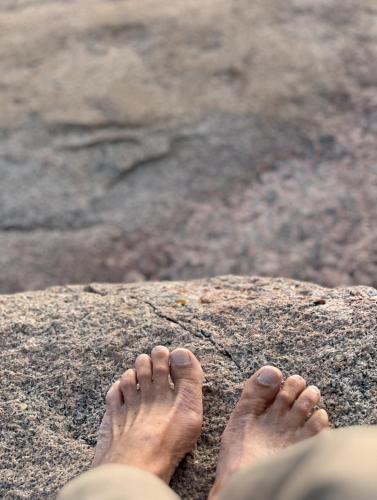 a persons feet on a rock on the beach at Atelier Blå houses in Rösselvik