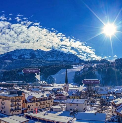 a view of a city with the sun and mountains at Appartement Jost - Nassfeld in Tröpolach