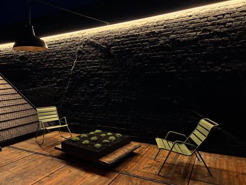 two chairs and a planter in a room with a brick wall at Les Camuches de la fonderie in Tournai
