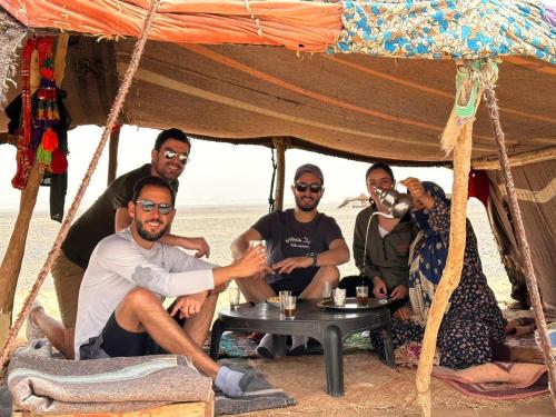 a group of people sitting under a tent on the beach at Alan Tent Merzouga in Merzouga