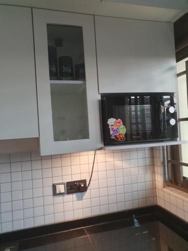 a kitchen with a microwave on a tiled wall at The Vault Heights Apartments in Kampala