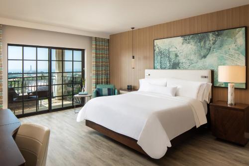 a bedroom with a large white bed and a balcony at The Westin Carlsbad Resort & Spa in Carlsbad