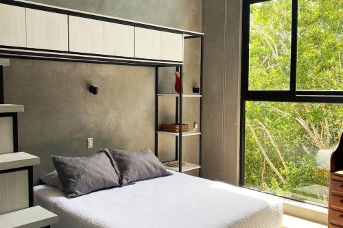 a bedroom with a bed and a large window at Tulum jungle penthouse in Chemuyil