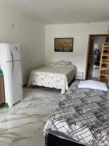 a room with two beds and a refrigerator at Residencial Europa in Bombinhas