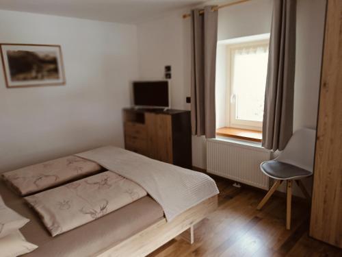 a bedroom with a bed and a chair and a window at Appartamenti Daberto Fabiola in Arabba