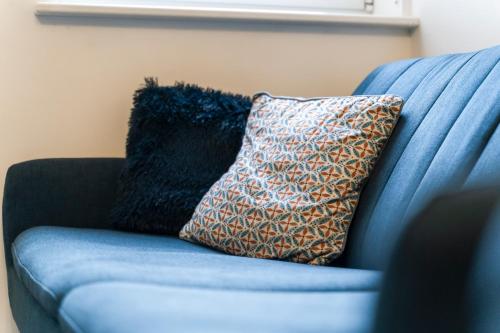 a blue couch with a pillow on it at OPK STAYS - Stylish City Centre 1 bed Apartment, Near train station, FREE parking Netflix, SLEEPS 4 in Coventry