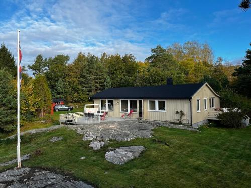 a small house with a flag in the yard at Delightful vacation home - boat - seaview - garden in Grimstad