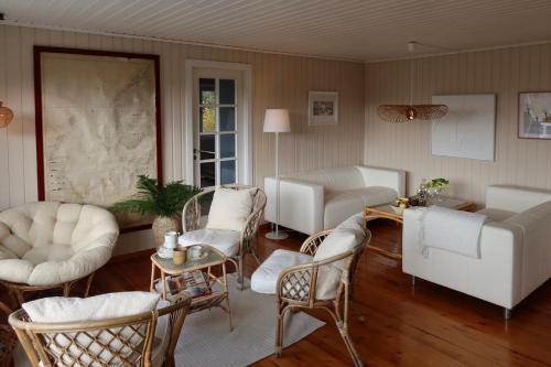 a living room with white chairs and a couch at Delightful vacation home - boat - seaview - garden in Grimstad